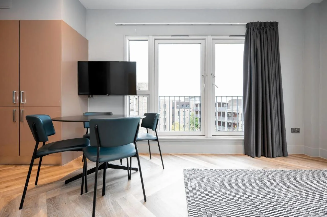 a dining room with a table and chairs and a large window at Staycity Aparthotels Edinburgh West End in Edinburgh